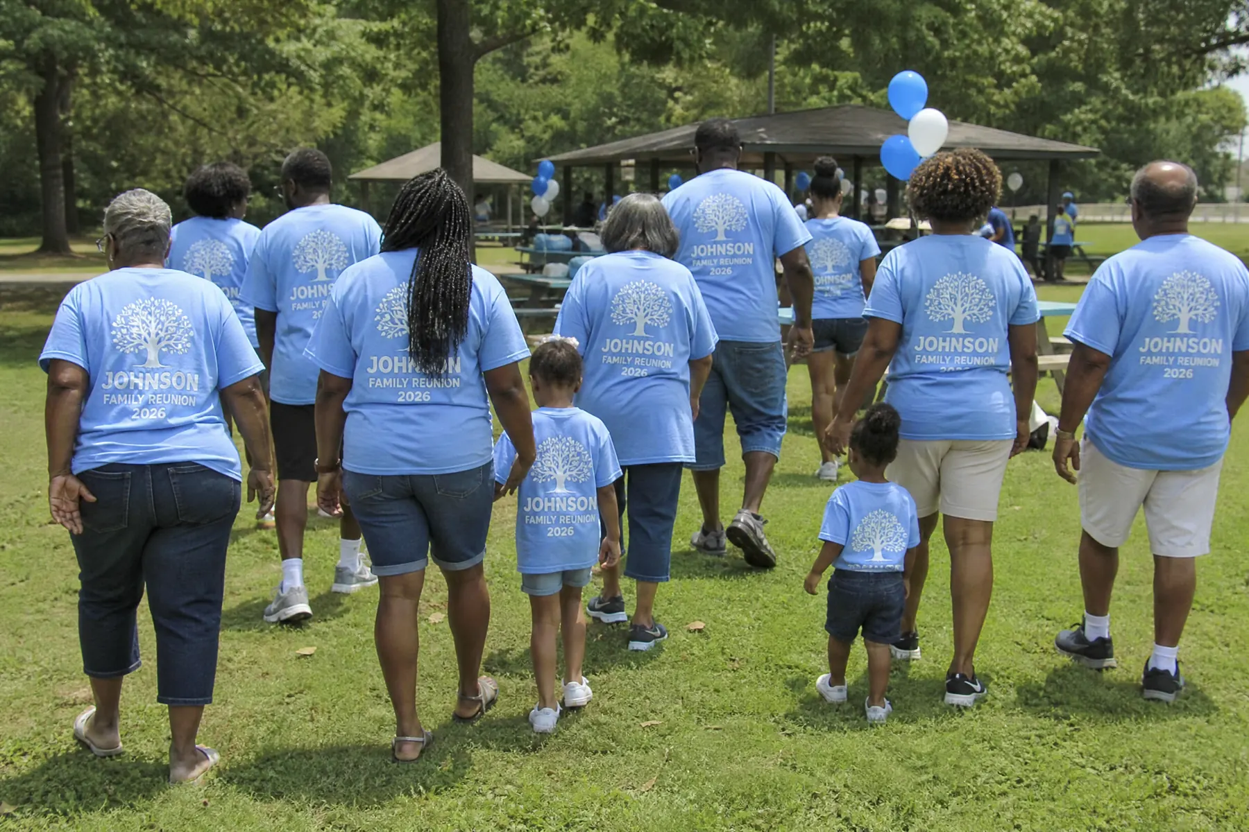 A family walking across the park in matching light blue Johnson Family Reunion shirts